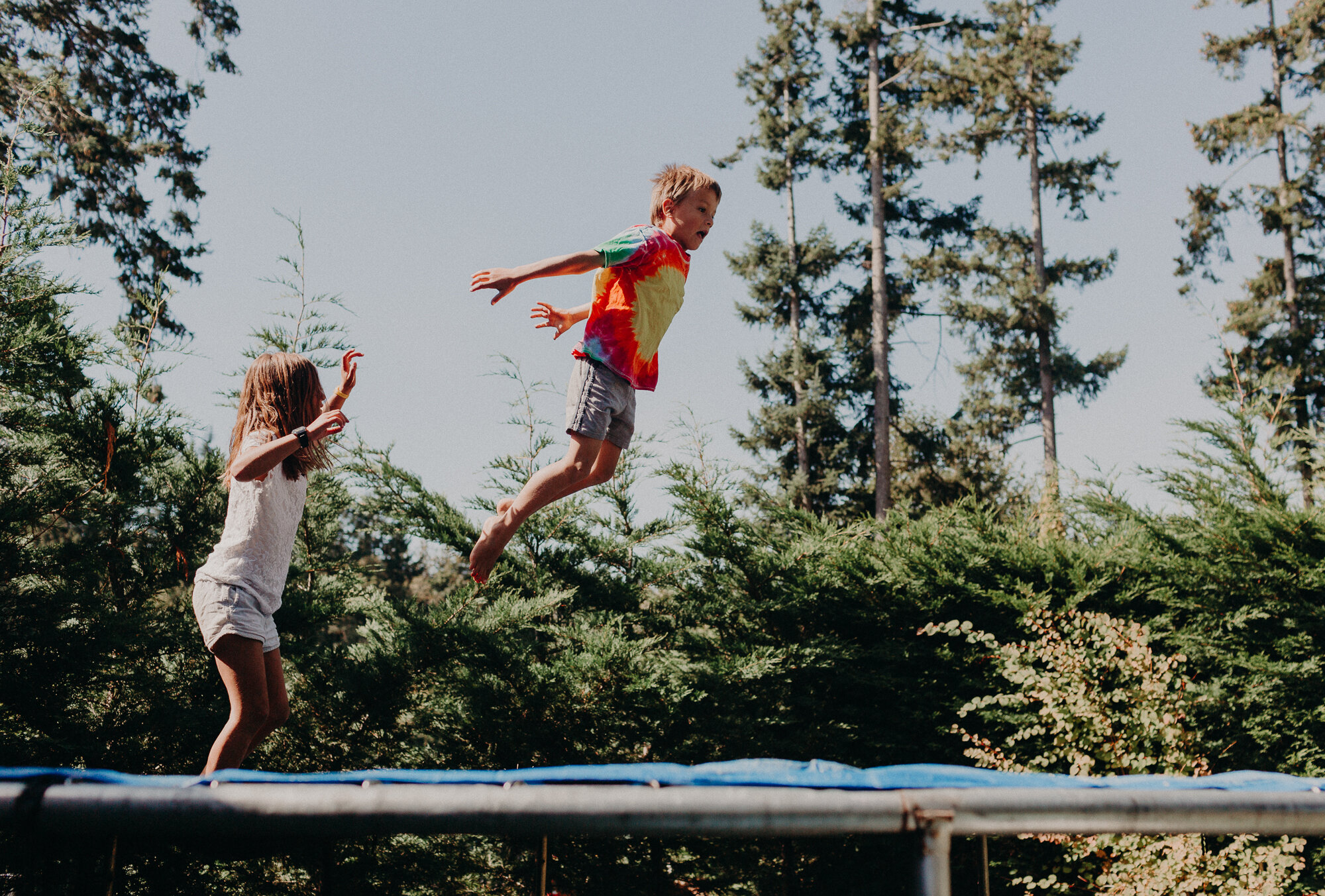 two kids jumping on trampoline in summer in Cowichan Valley photo session