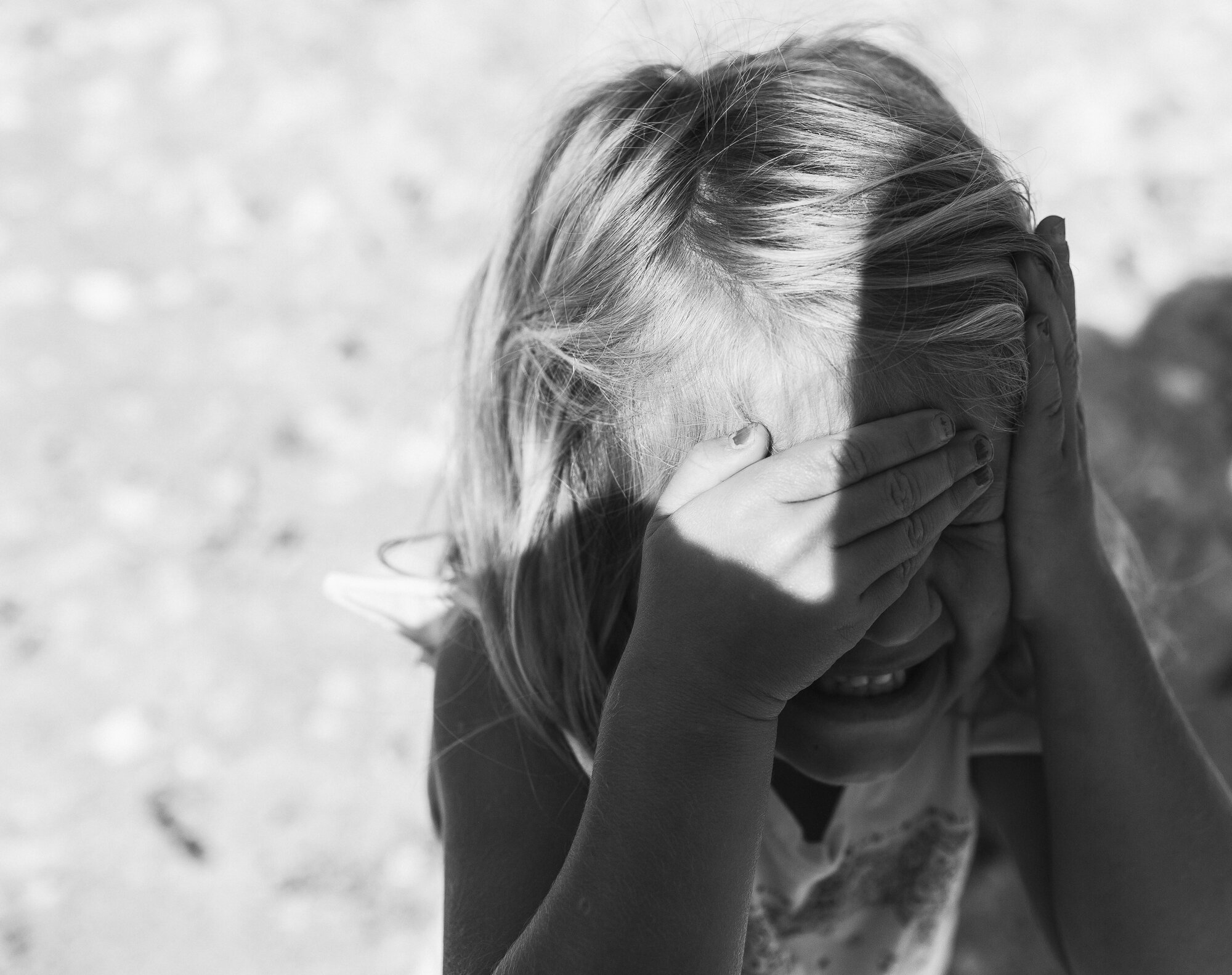 Funny shy girl hiding face from camera in black and white family photo session