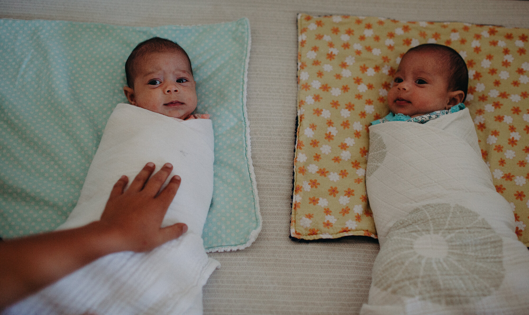 two newborn baby twins swaddled in their crib