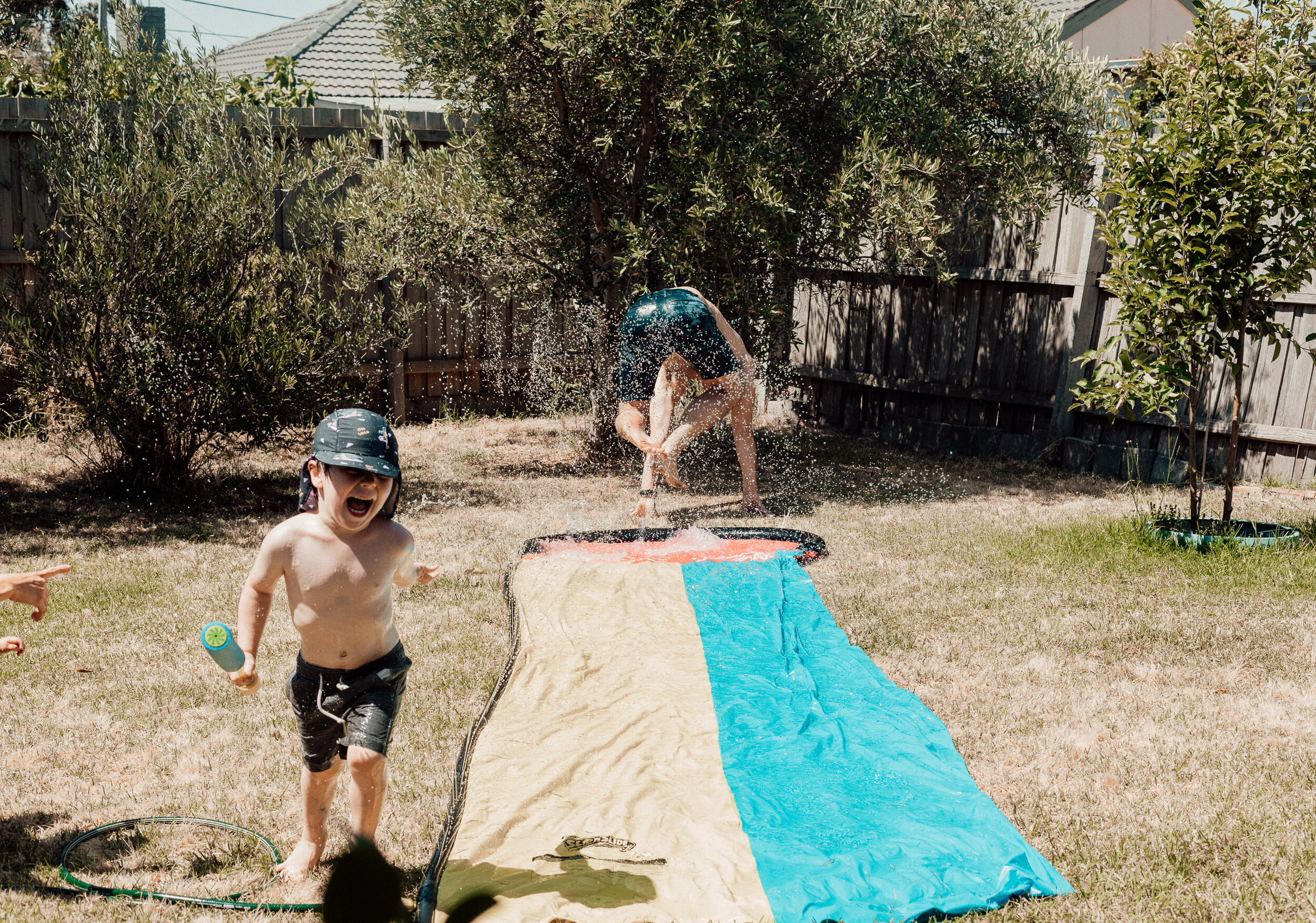Toddler and man play on slip n slide at a hot family Christmas in Melbourne.jpg