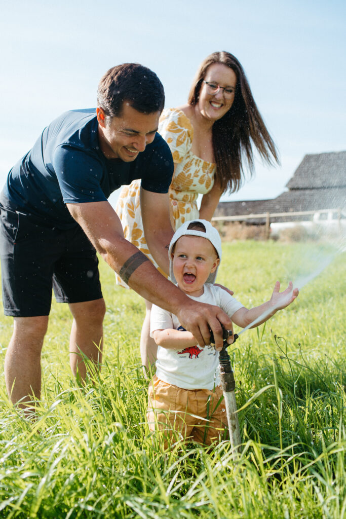 Young boy squirts his parents with the sprinkler.
