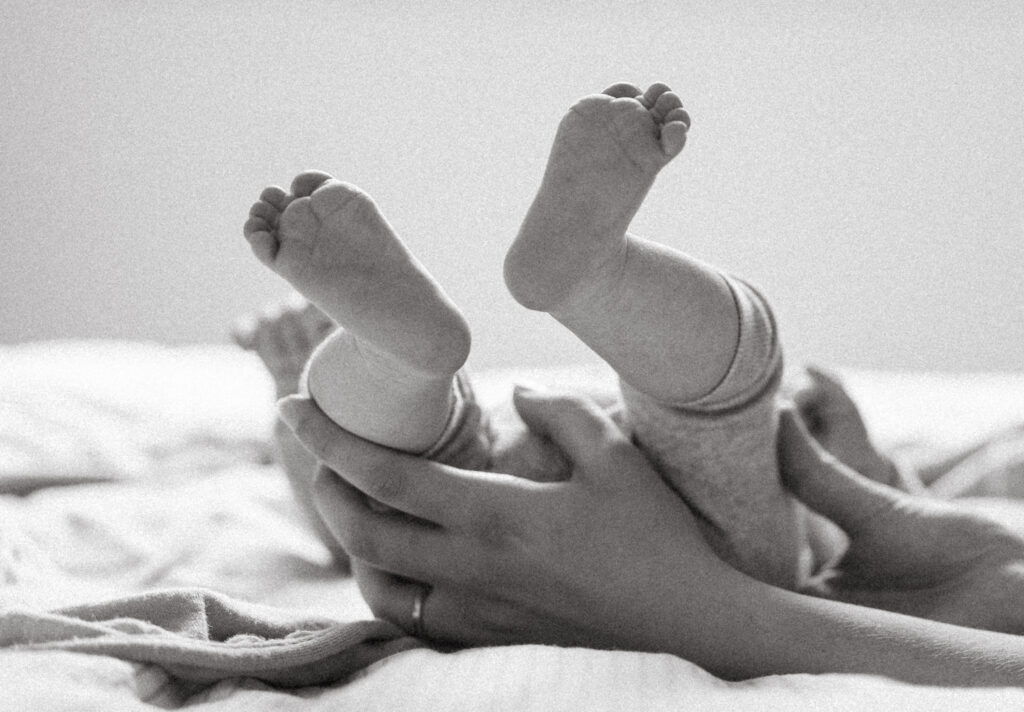 Black and white photo of mum holding her newborn's toes.