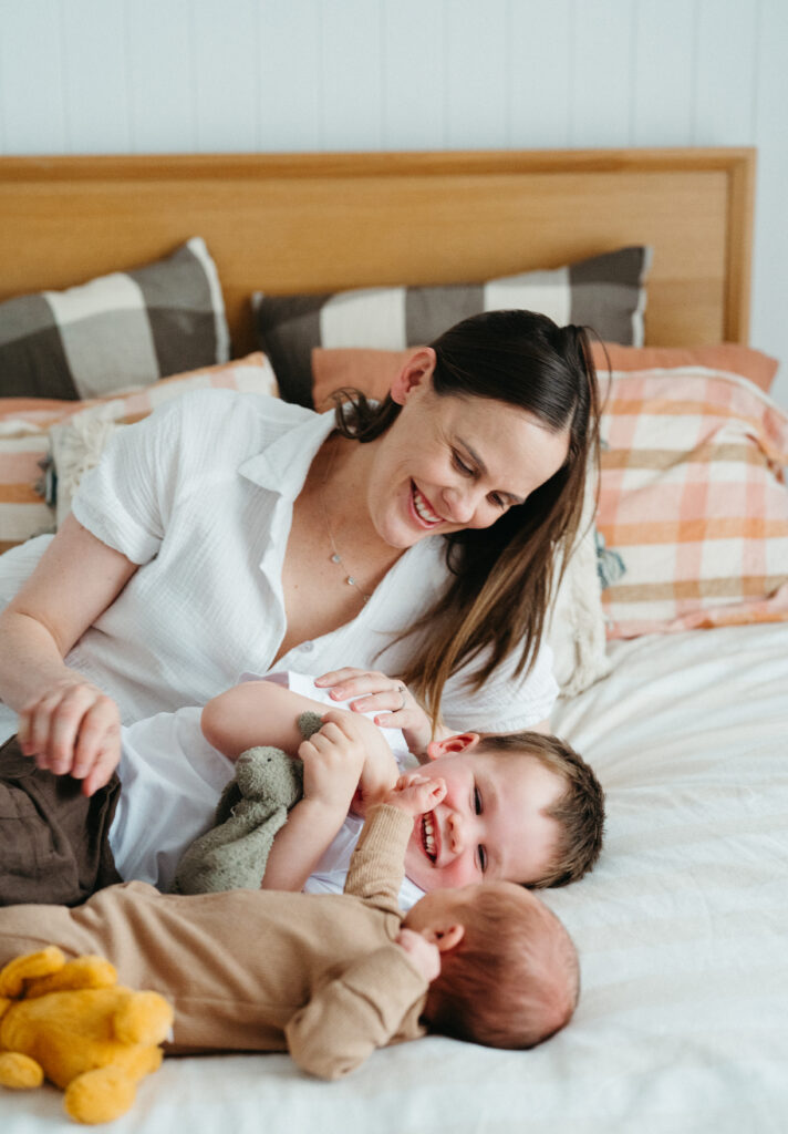 Mother and toddler cuddle newborn baby on the bed in a Geelong newborn photography session.