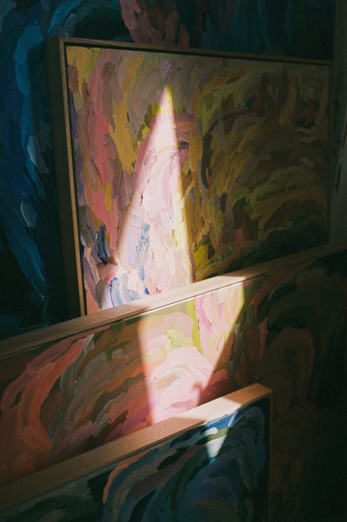 Erin Reinboth's art stacked up with a sliver of light on the paintings in her studio, shot on film