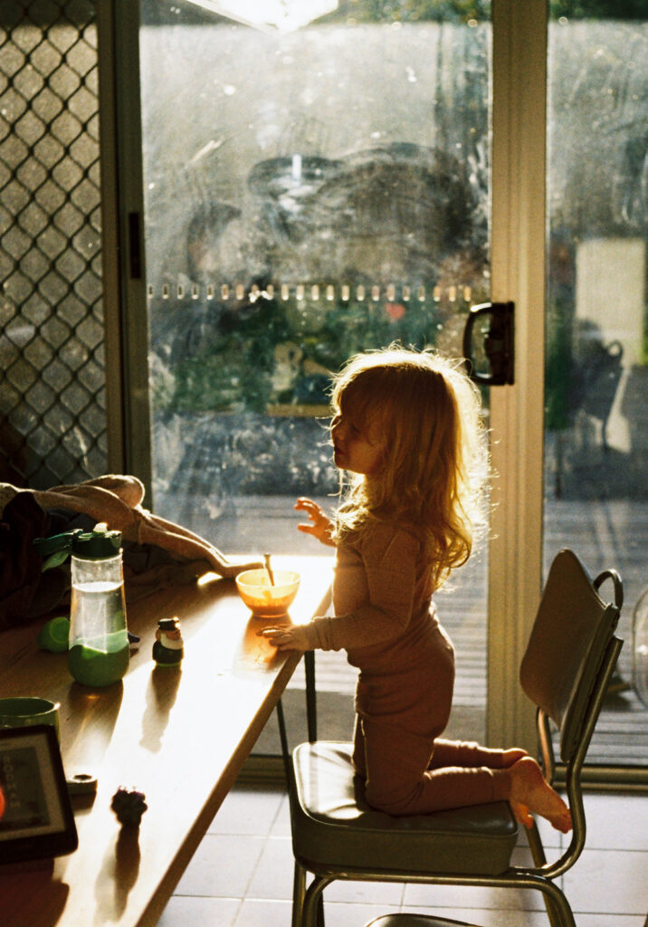 little girl eating breakfast with light streaming in through dirty windows