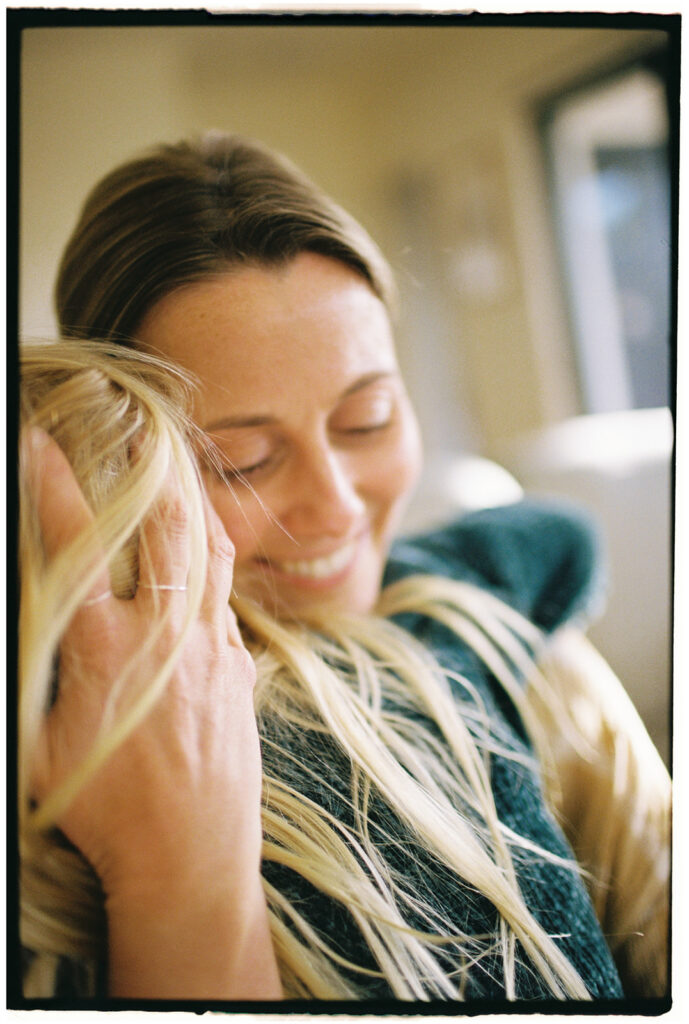 mother hugs her daughter with sunlight on her hair in jan juc family photo session with bobby dazzler photography