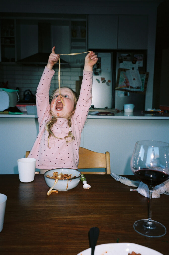 funny photo little girl eating a really long piece of spaghetti by bobby dazzler photography
