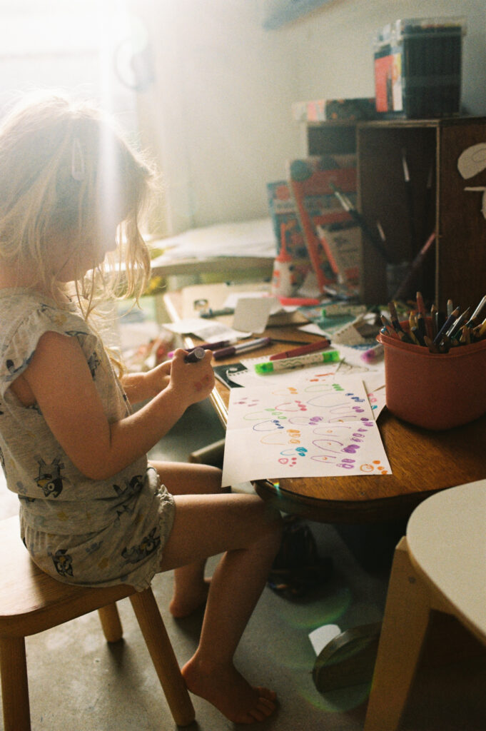 sunlight through window as little girl draws a picture during family film photoshoot with bobby dazzler photography in torquay australia